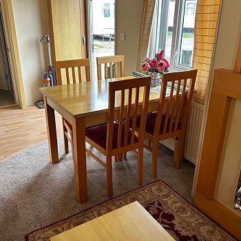 A wooden dining table inside the green Swift Mosell caravan