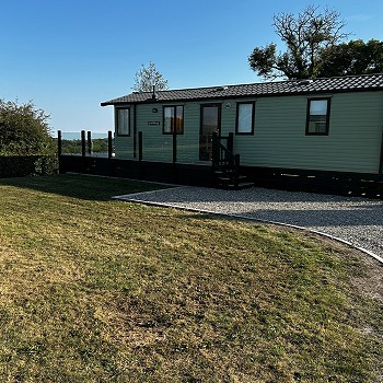 Outside of the green Swift Mosell caravan with a garden next to it